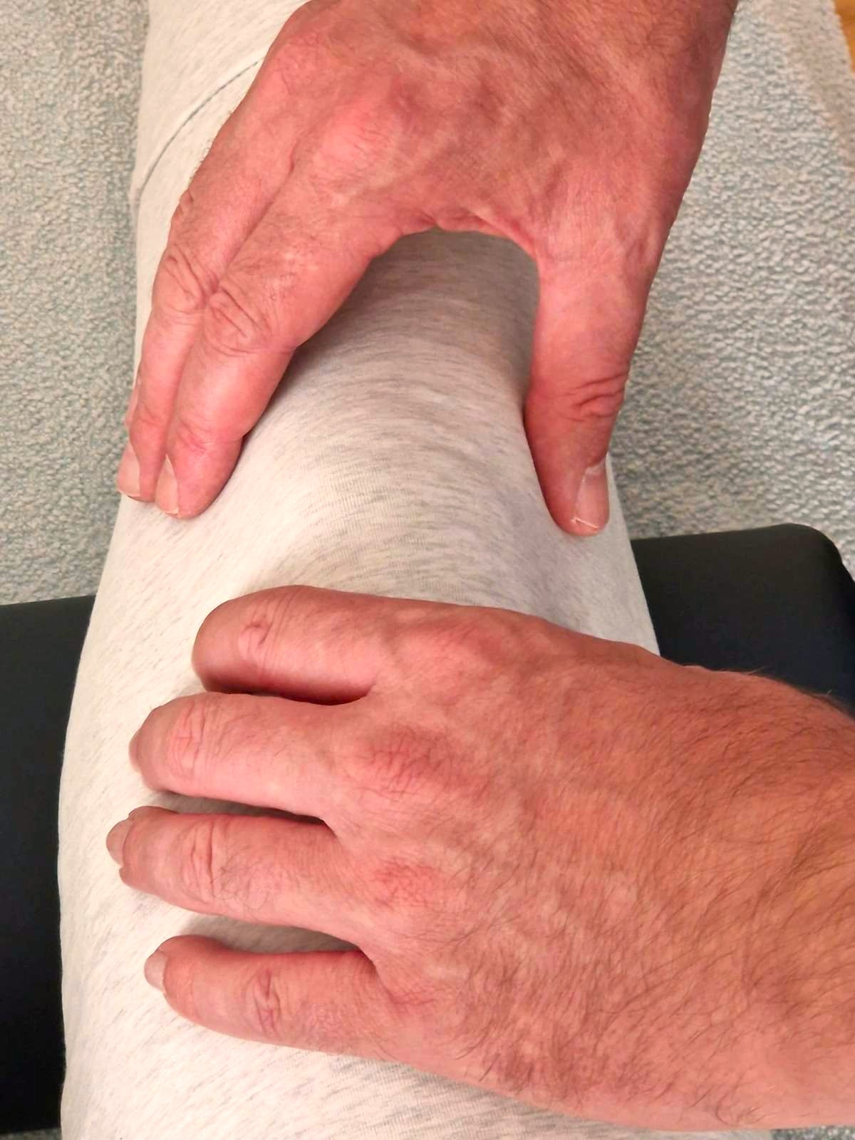 Zwei Hände berühren ein Knie